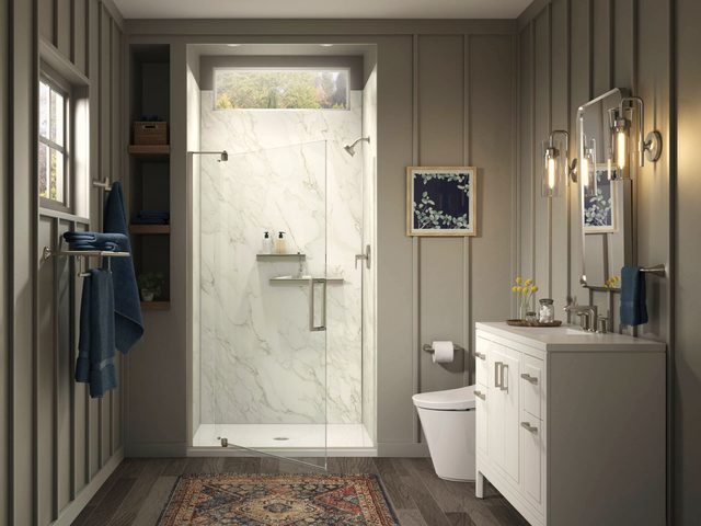 White marble shower enclosure beside board-and-batten panelled walls, with navy towels on a rail.